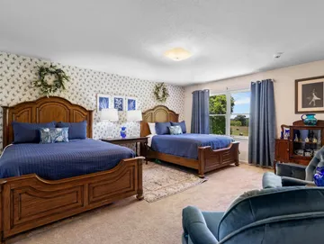 A bedroom with two beds , a chair and a window.