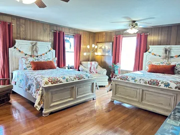 A bedroom with two beds , a chair and a ceiling fan.