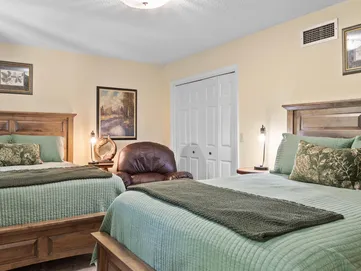 A bedroom with two beds , a chair and a closet.