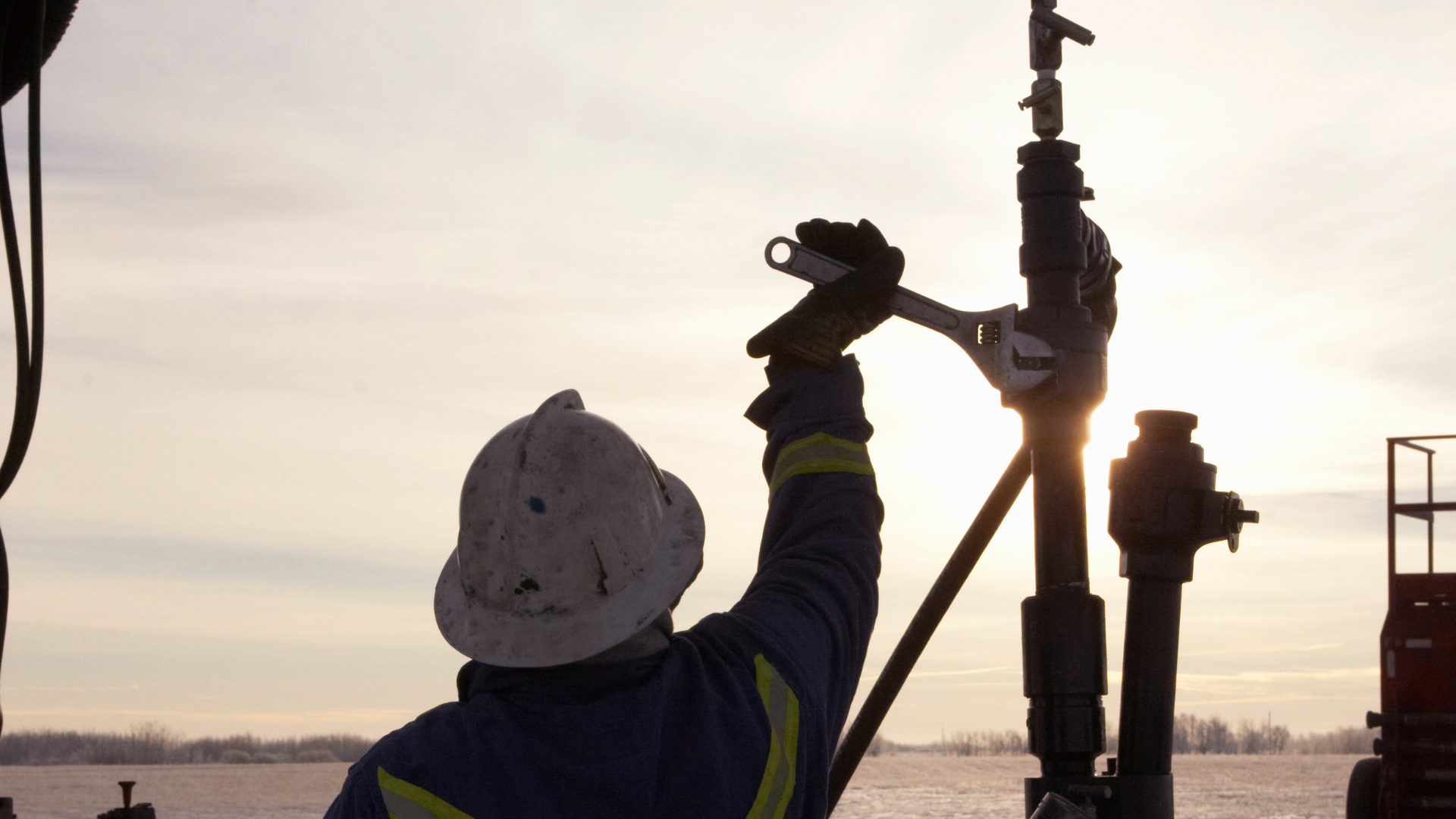 A man in a hard hat is working on a pipe with a wrench.