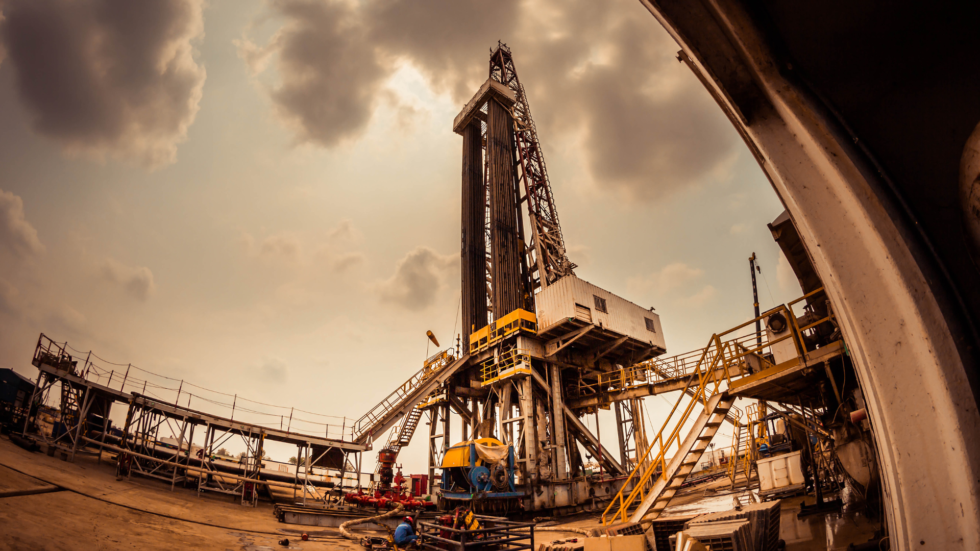 A large oil rig is sitting on top of a dirt field.