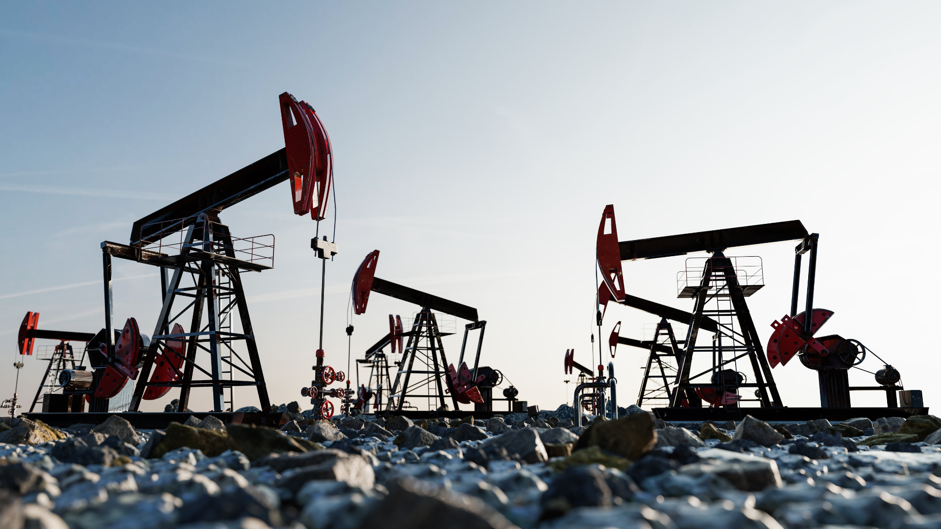 A group of oil pumps are sitting on top of a rocky field.