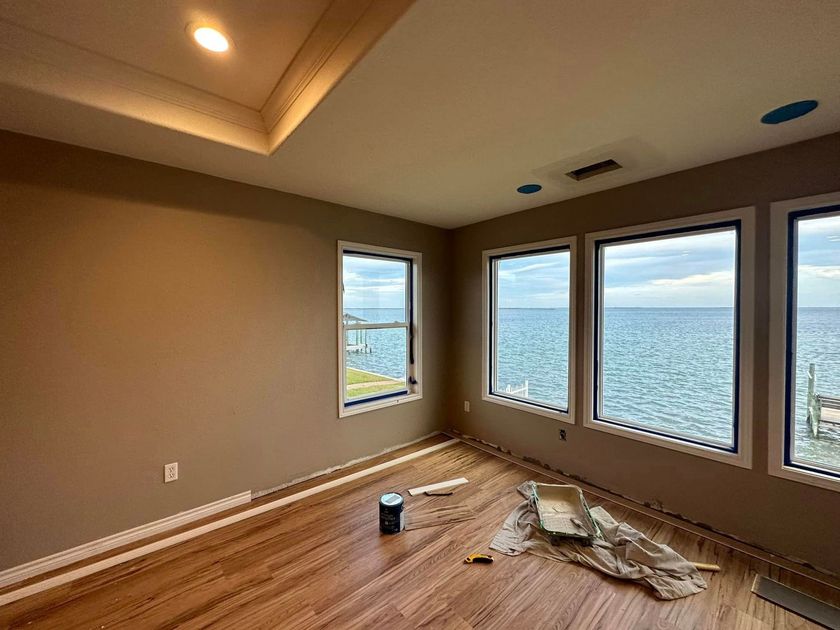 an empty room with hardwood floors and lots of windows overlooking the ocean