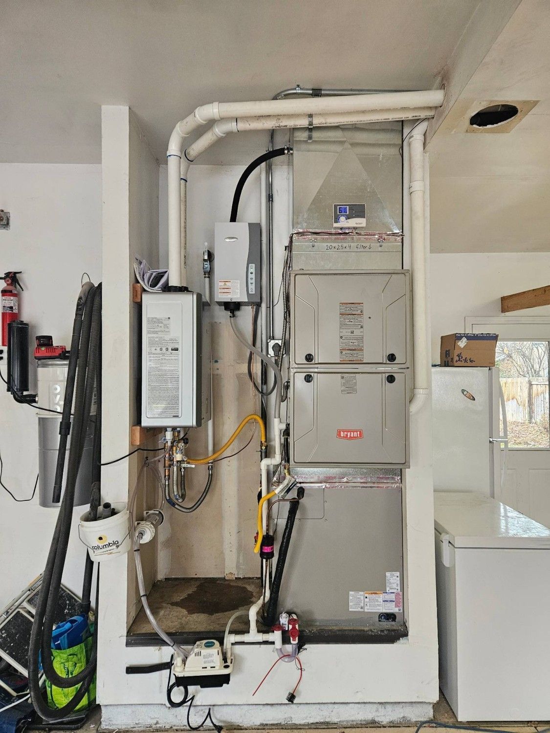 Utility equipment with gray electrical panels, white piping, and hoses installed in a garage-like room