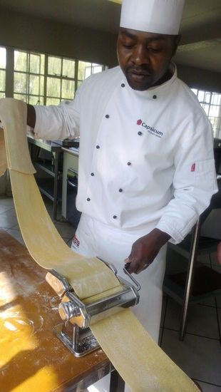 A chef is making pasta with a machine in a kitchen.