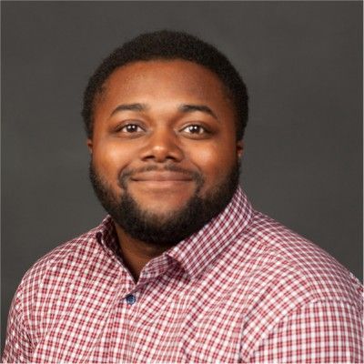 A man with a beard and a suit is smiling for the camera.