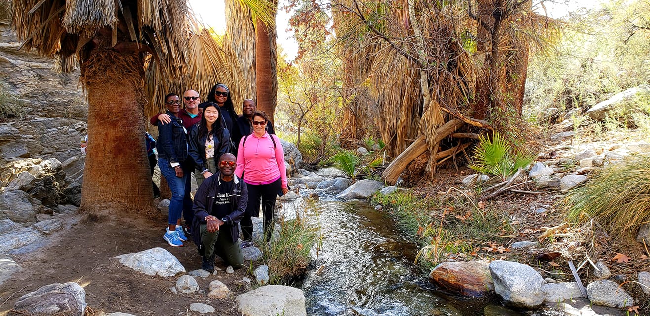A group taking a through posing for a picture near running water in the Indian Canyon Walking Tour