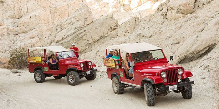Two red jeep with people inside