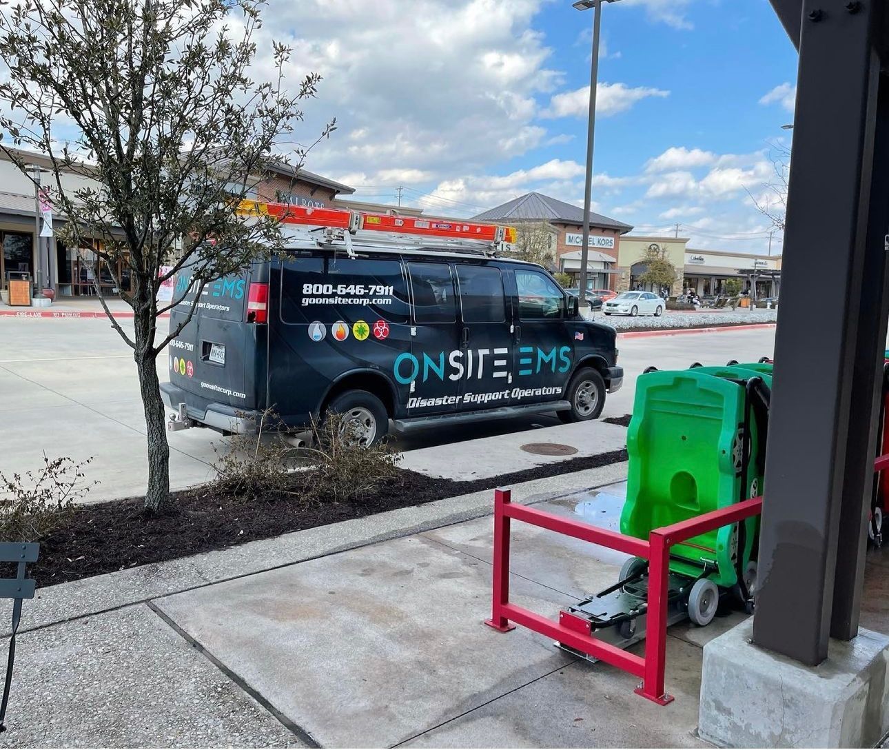 A black van with the word onsite ems on the side is parked in a parking lot.