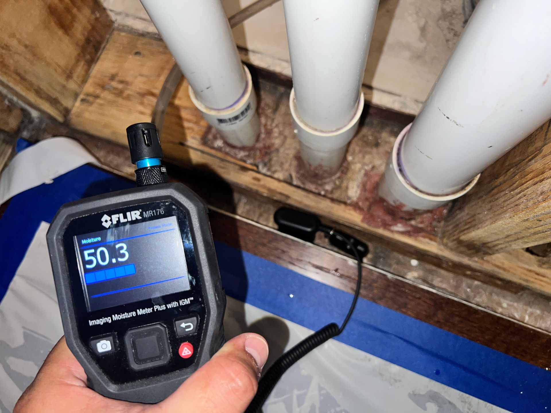 A person is holding a flir camera in front of pipes.