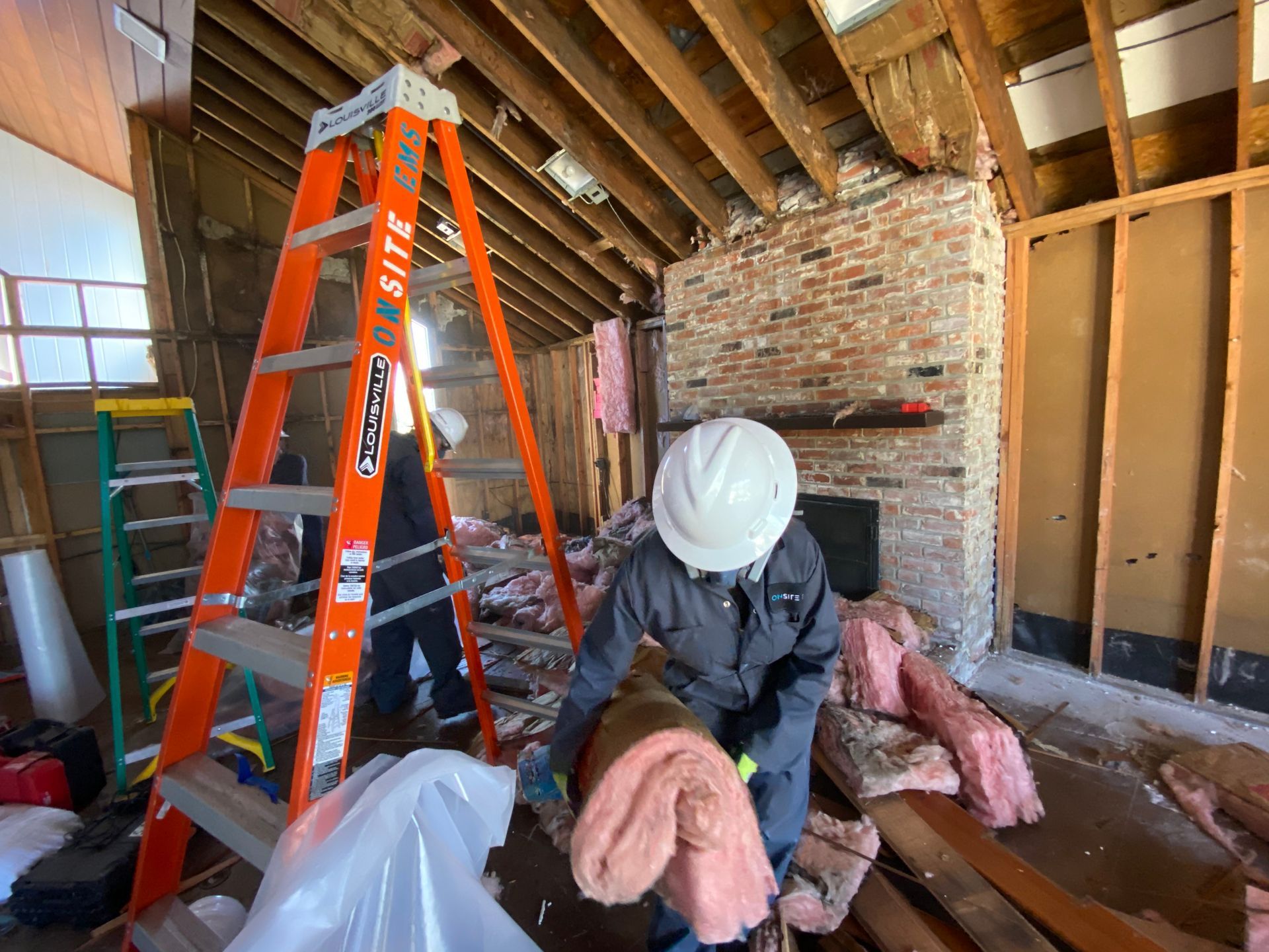 A man is standing next to a ladder in a room.