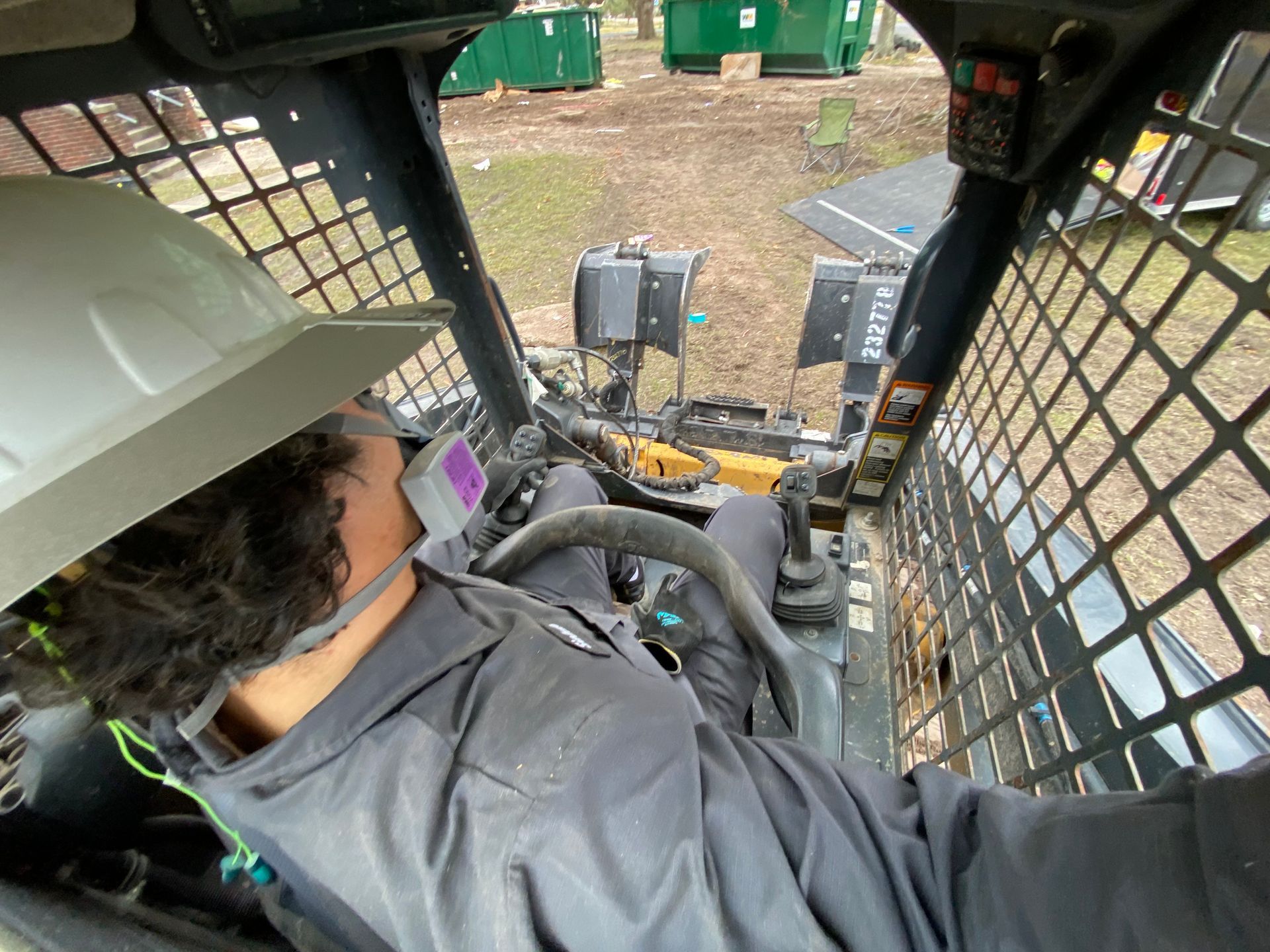 A man wearing a hard hat is driving a construction vehicle.