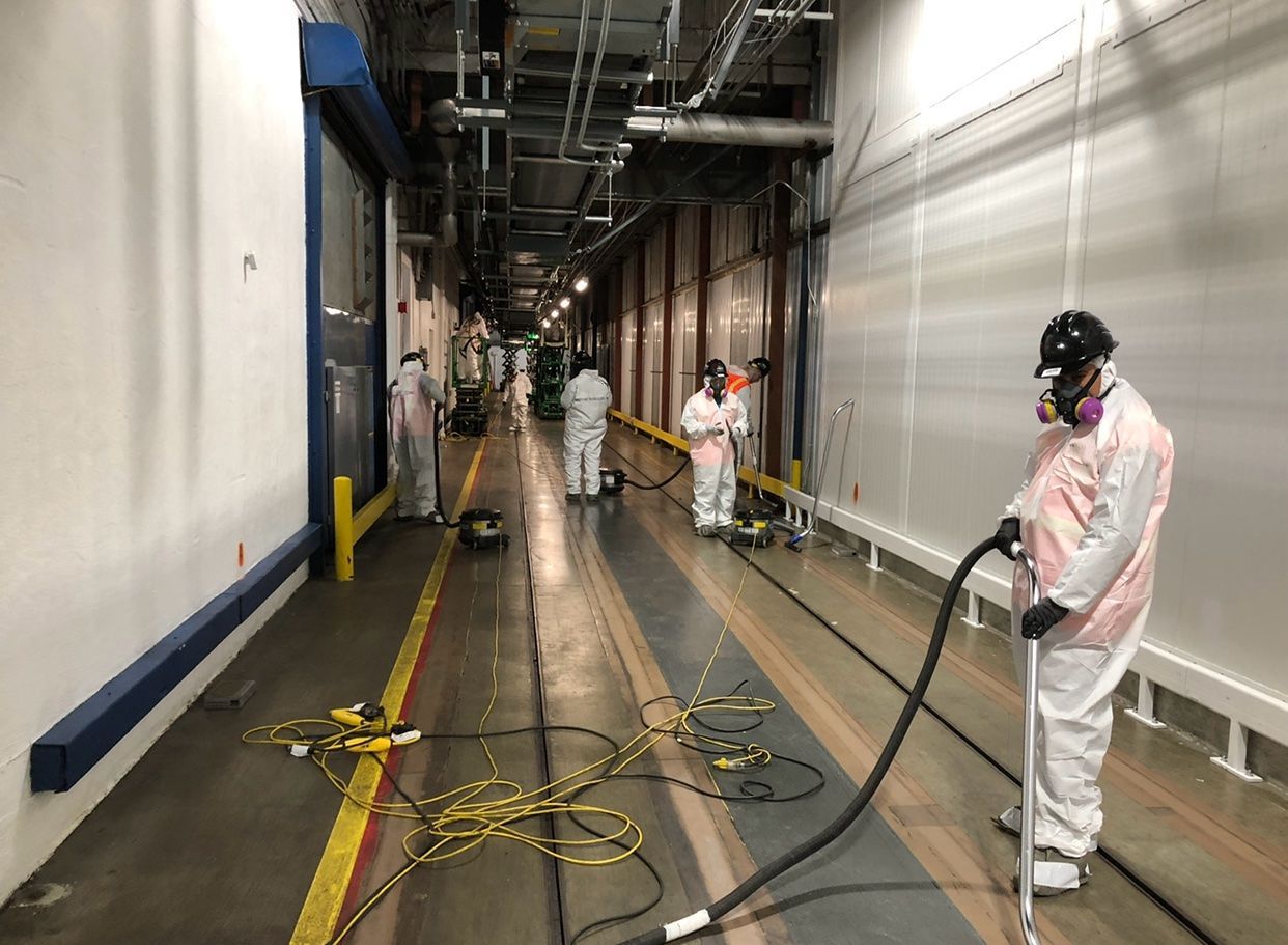 A group of people are cleaning a building with a vacuum cleaner.