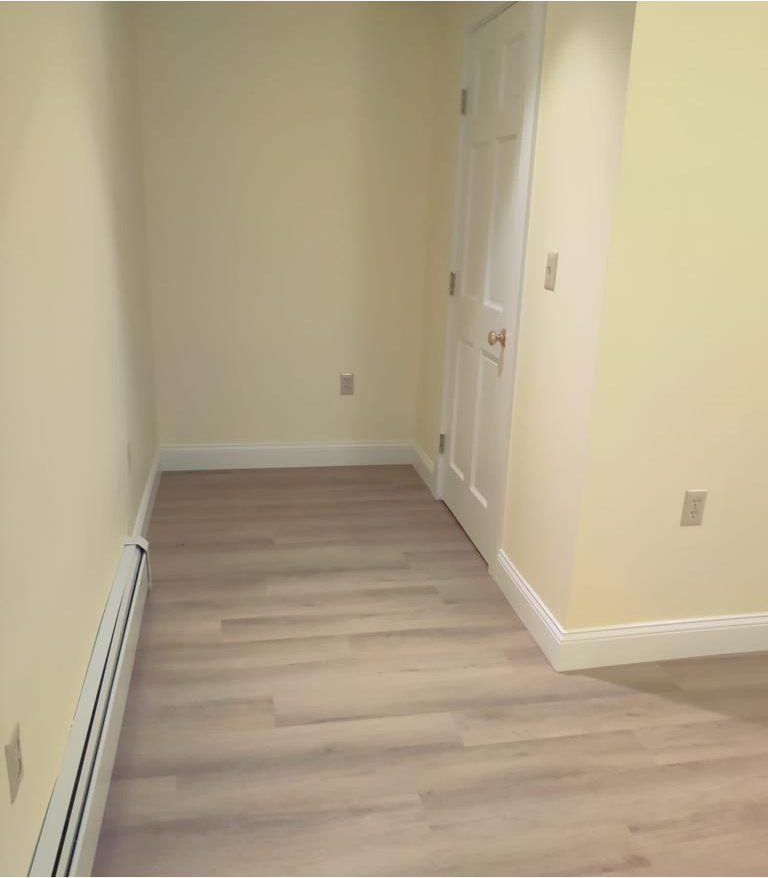 An empty room with hardwood floors and a door.