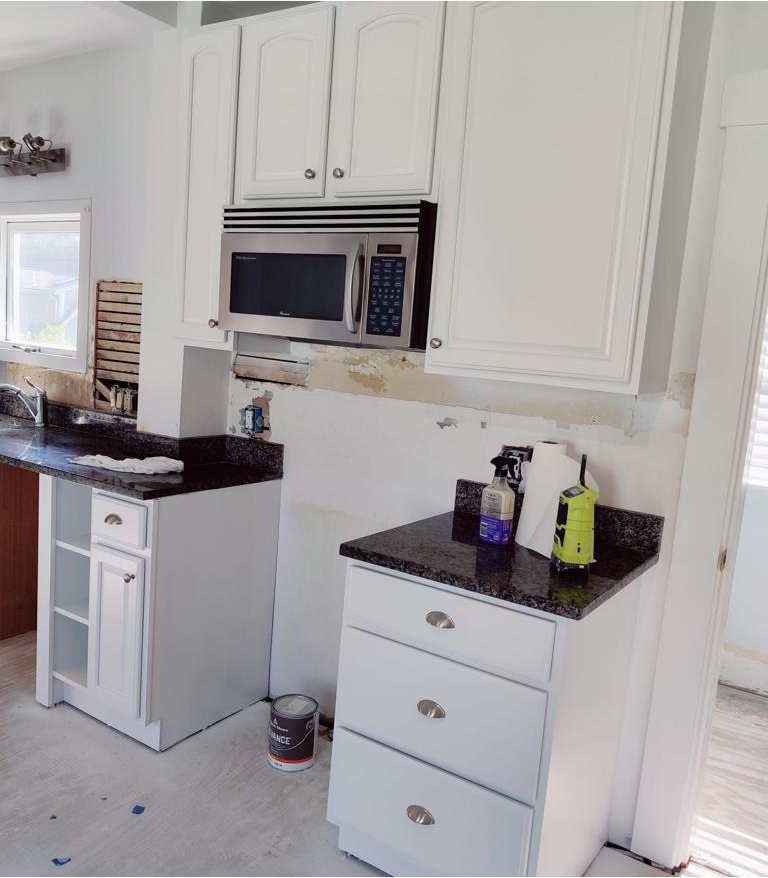 A kitchen with white cabinets and a stainless steel microwave