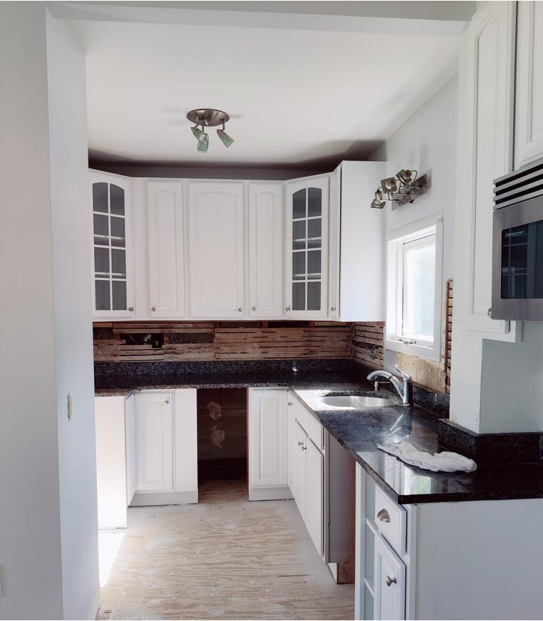 A kitchen with white cabinets and black counter tops