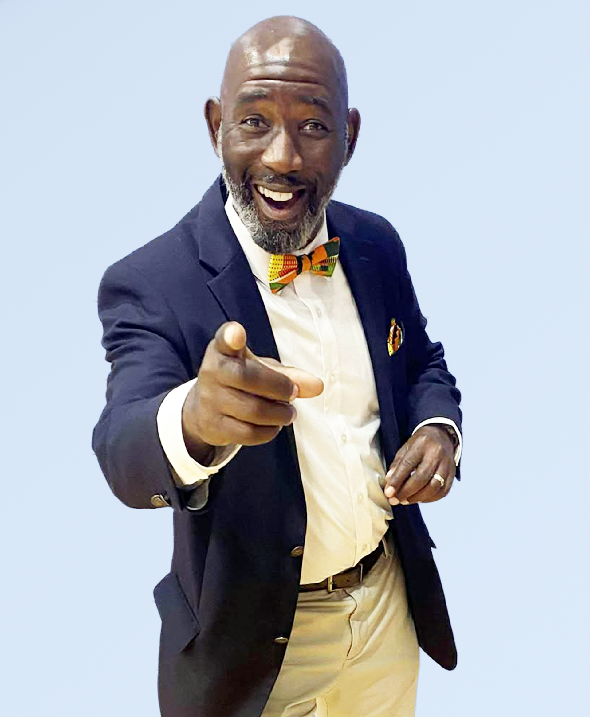 Anthony Clements smiling confidently in a navy blazer, white shirt, and orange bow tie against a light blue background, symbolizing positivity and charisma.