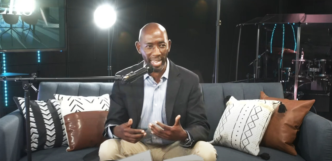 Anthony Clements speaking passionately during an interview on Freedom Talks, seated on a modern couch with studio lighting and stage equipment in the background.