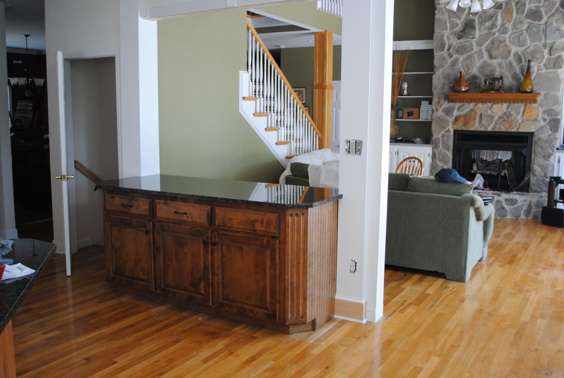 A living room with hardwood floors a staircase and a fireplace