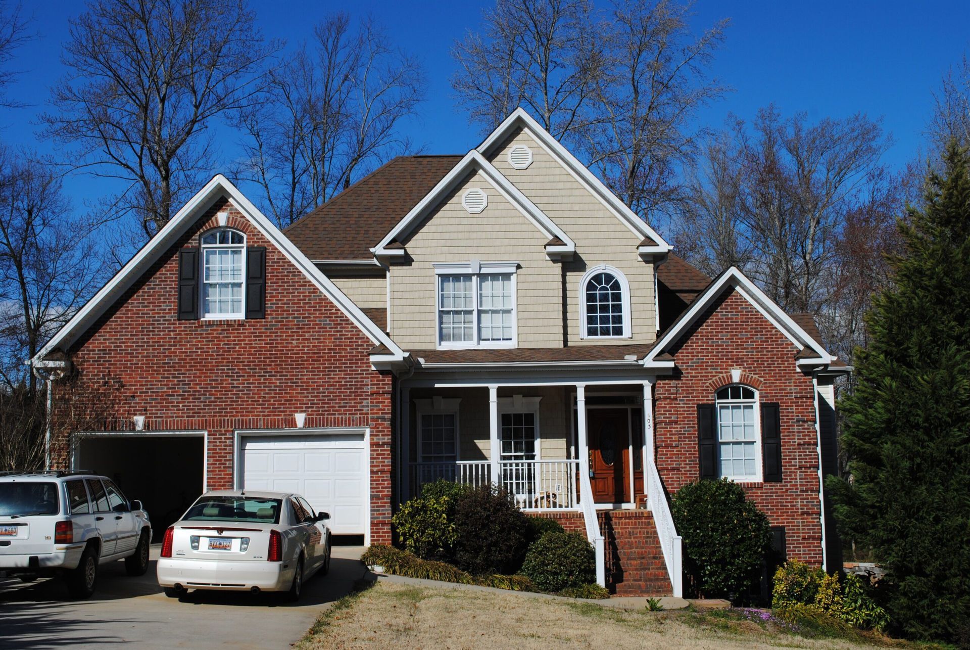 A brick house with two cars parked in front of it
