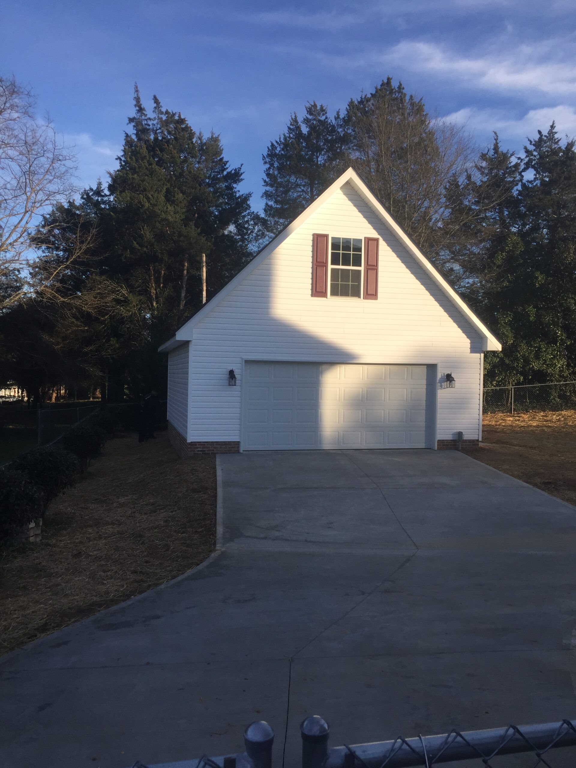 A white garage with red shutters and a driveway