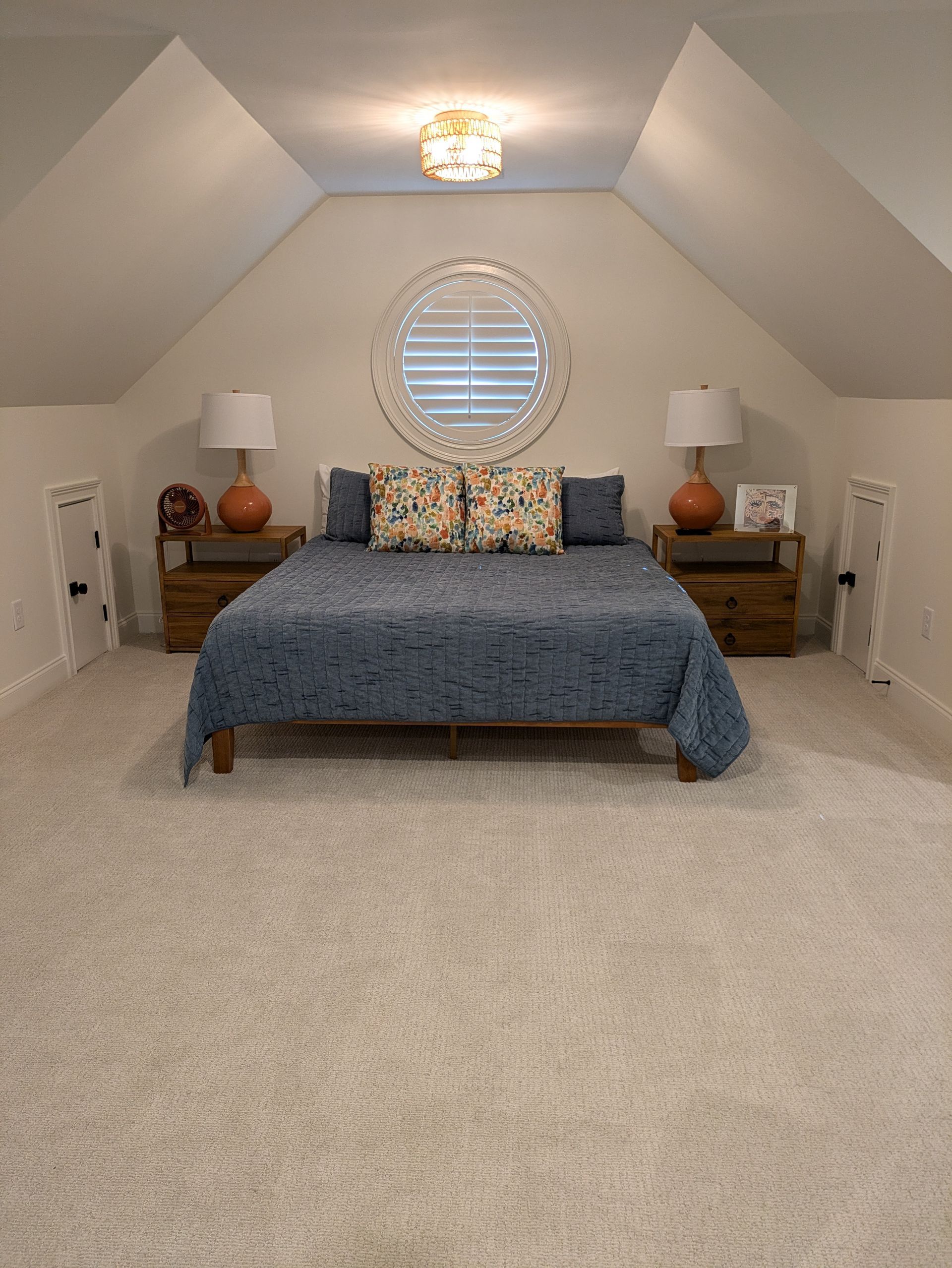 A bedroom with a bed , nightstands , lamps and a window.