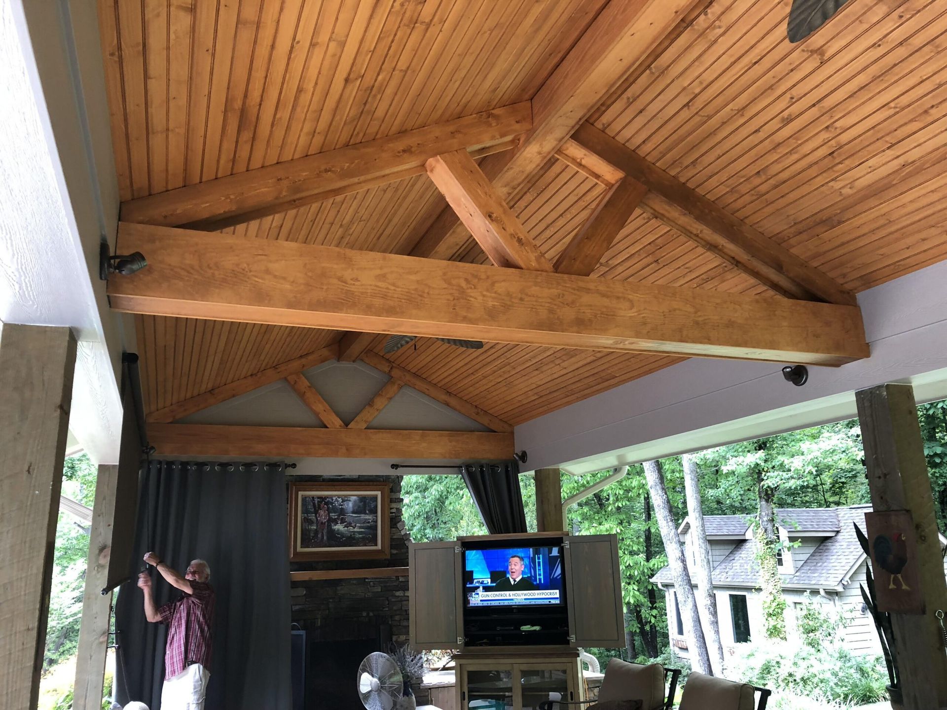 A living room with a wooden ceiling and a flat screen tv.