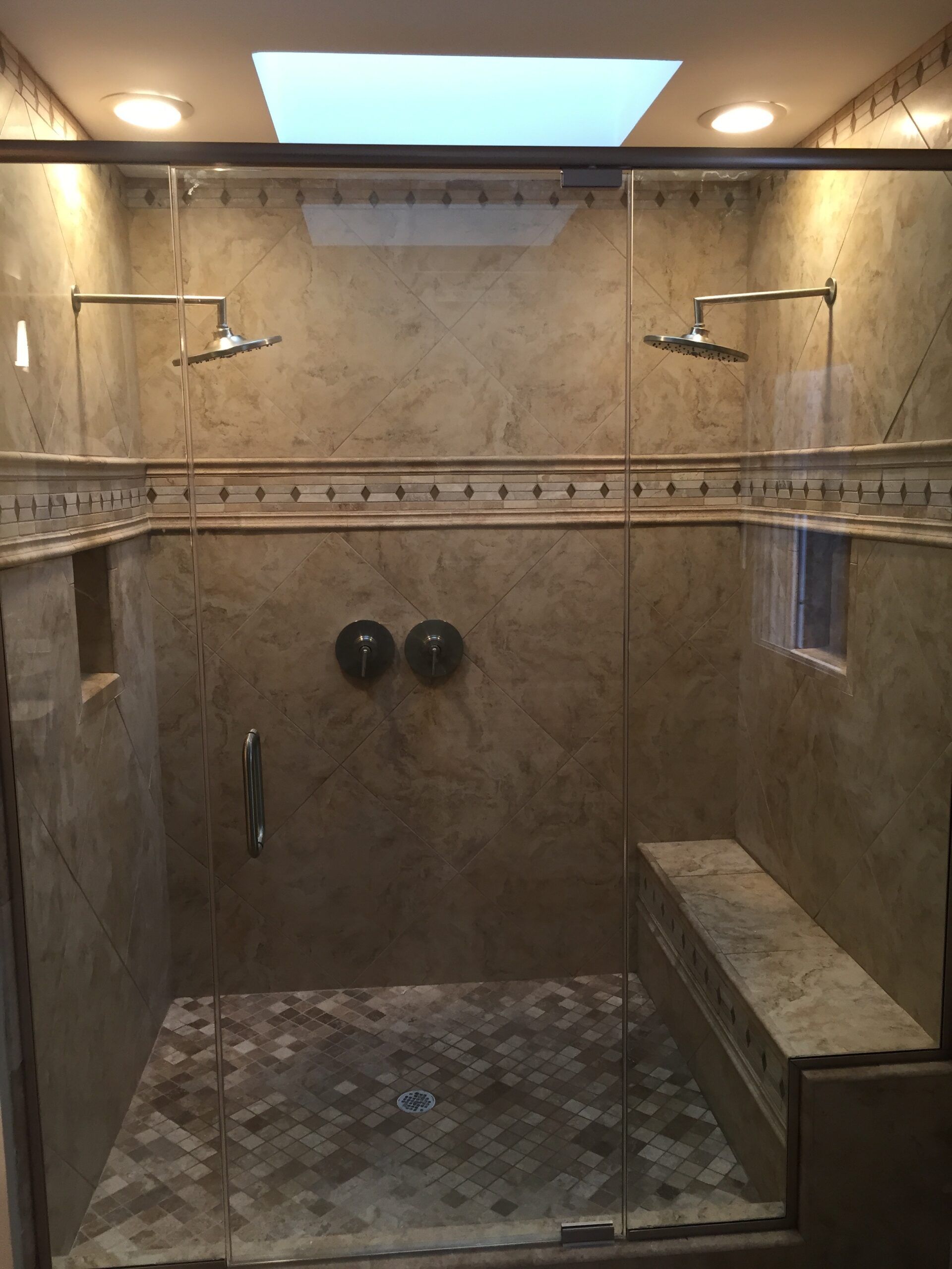 A shower with two shower heads and a skylight above it.