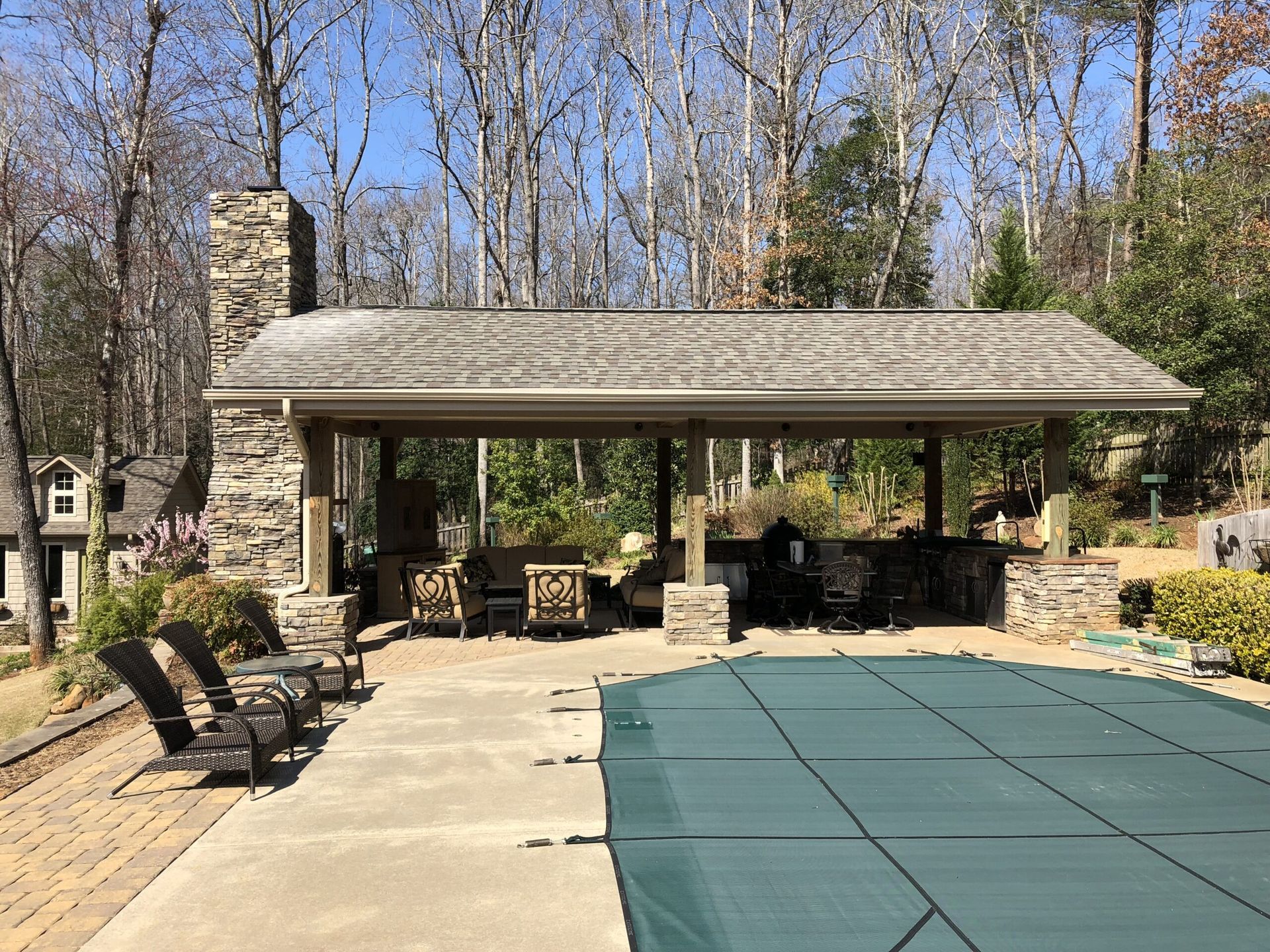 A pool with a green cover and a pavilion in the background.