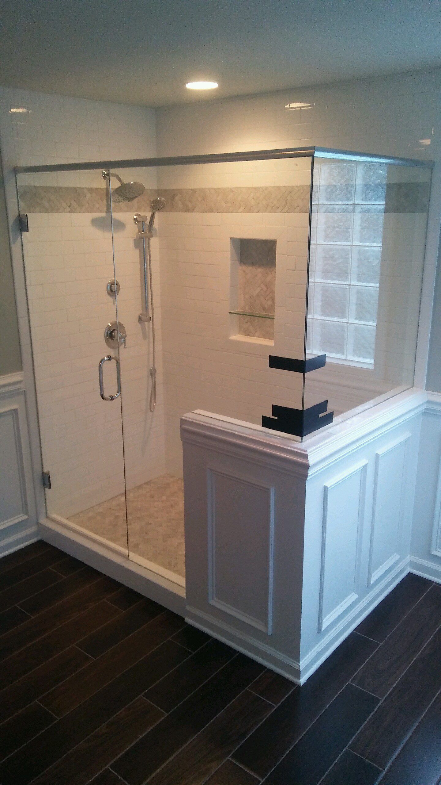 A bathroom with a walk in shower and a window.