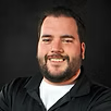 A man with a beard is smiling and wearing a black shirt.