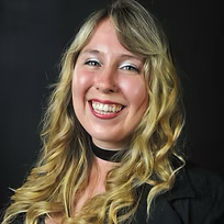 A woman with long blonde hair is smiling and wearing a choker.