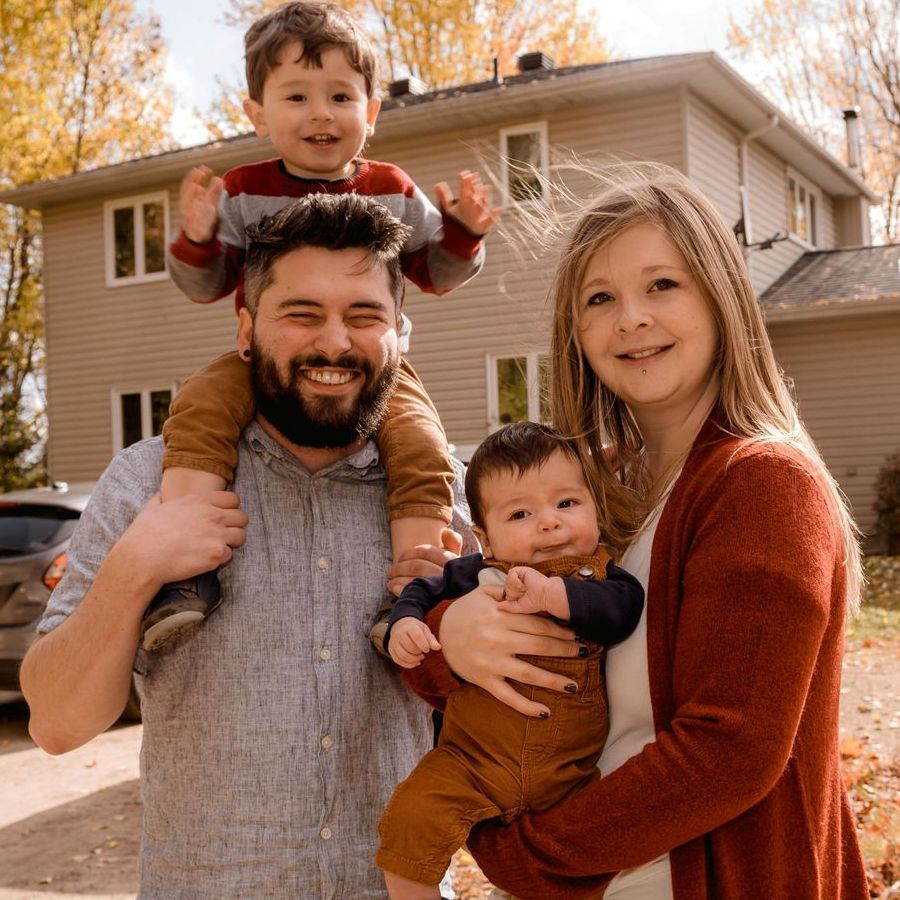A family is posing for a picture in front of a house.