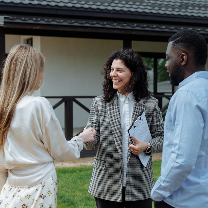 A man and a woman are shaking hands in front of a house.