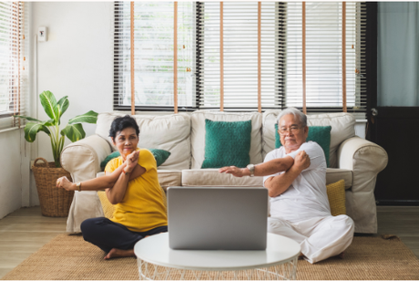 A picture of an older couple sitting on the ground stretching.