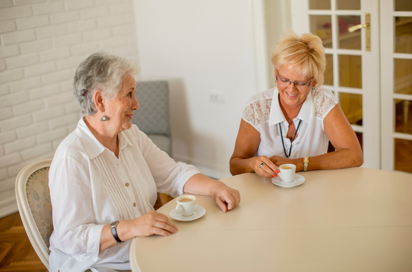 A picture of two woman sitting at a table drinking coffee.