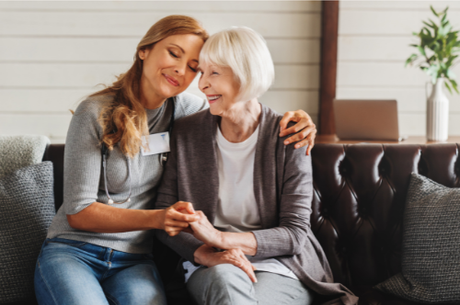 A picture of a woman hugging an older lady on a sofa