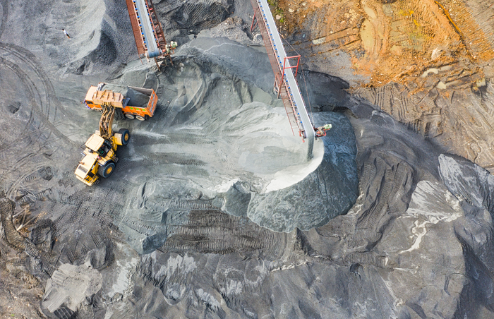 Aerial view of an industrial mining operation with machinery, conveyors, and piles of aggregate.
