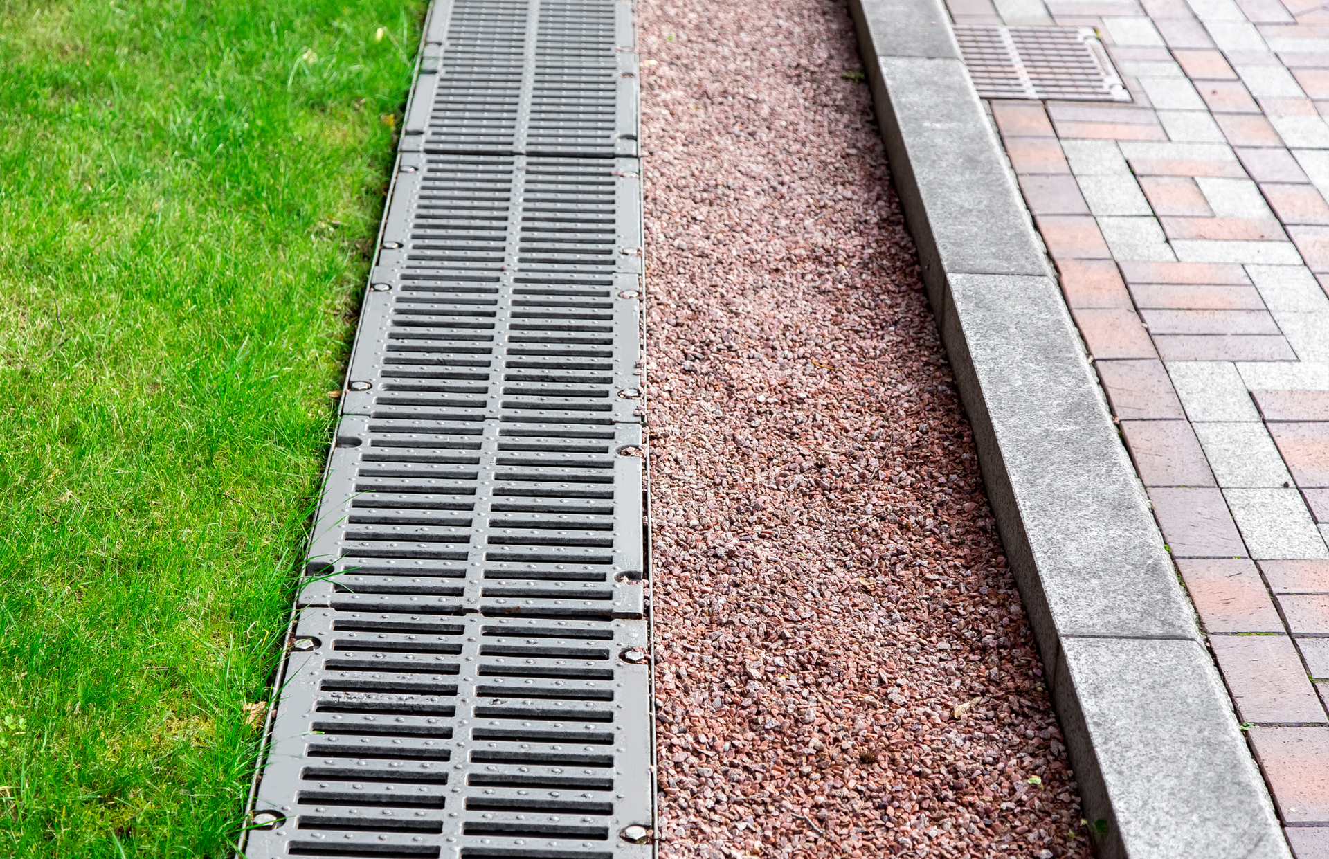 A yellow excavator demolishing a brick building, with rubble and dust in the air.