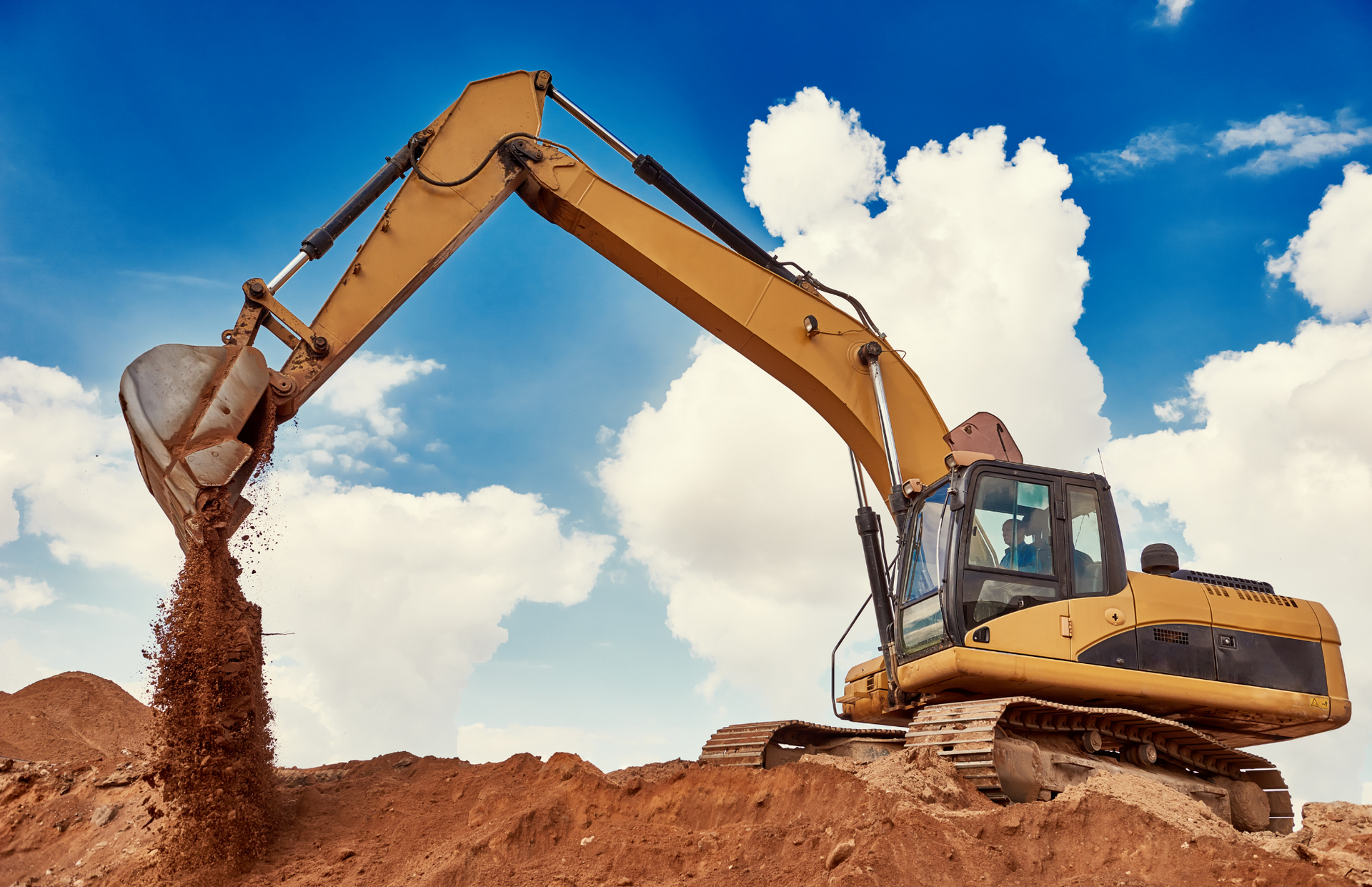 Yellow bulldozer on a construction site, moving piles of tan-colored material. Aerial view.