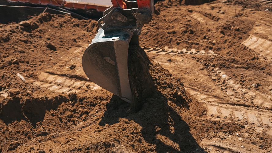 Yellow front-end loader on a construction site, moving yellow material, creating textured patterns in sand.