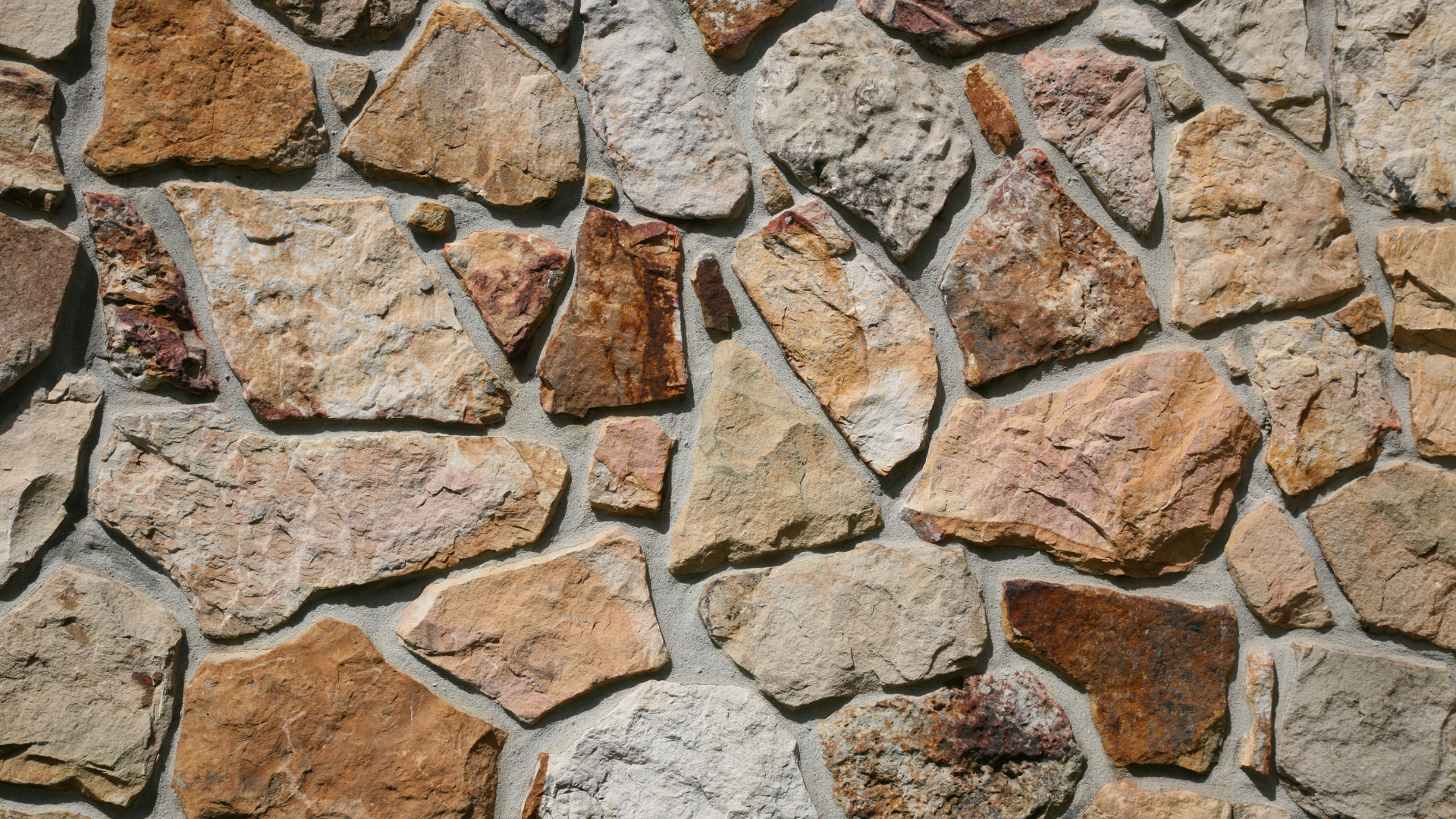 Stone wall with irregularly shaped rocks in shades of brown and beige.
