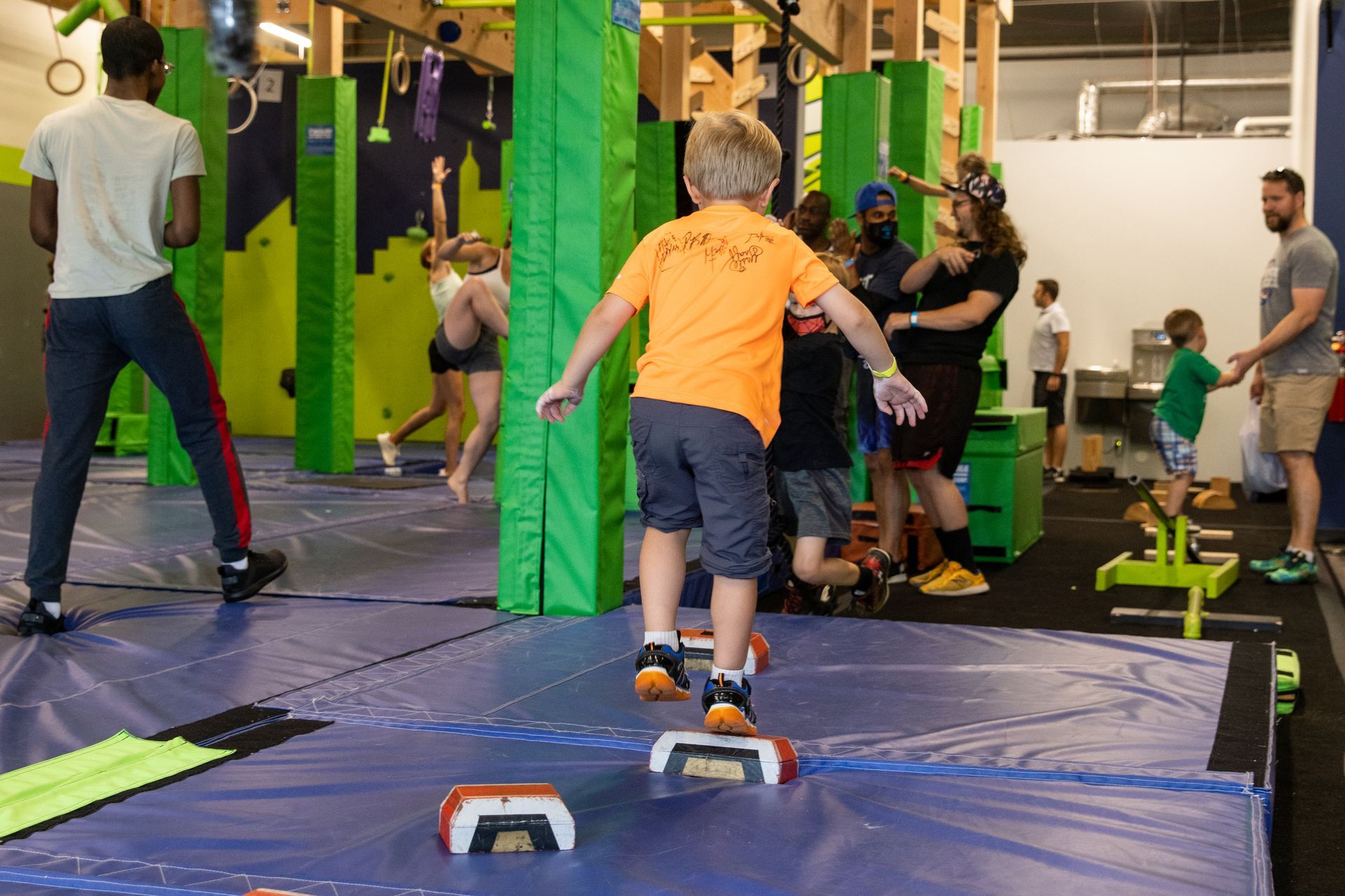 A young boy is jumping on a mat in a gym.