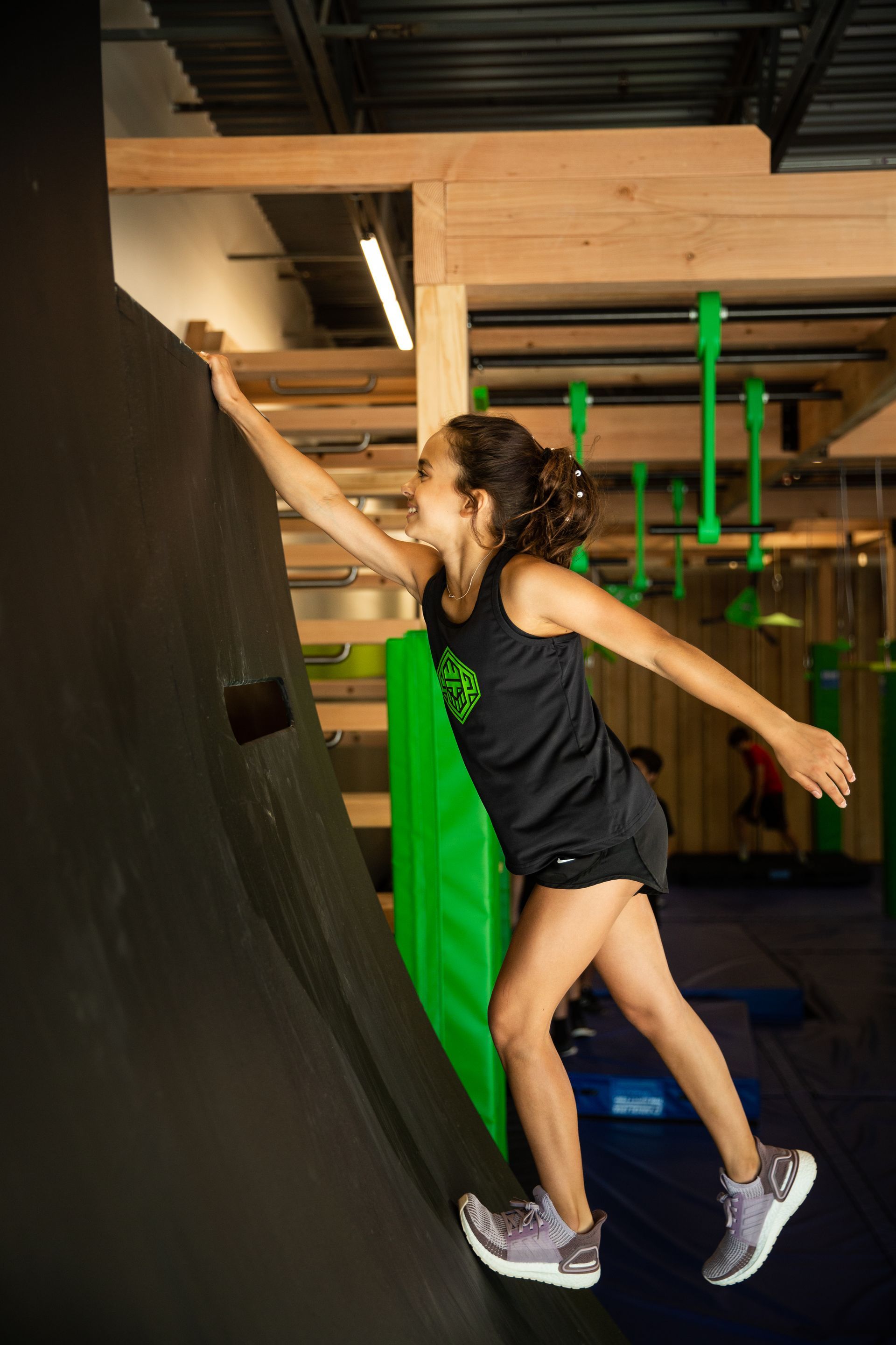 A young girl is climbing a wall in a gym.
