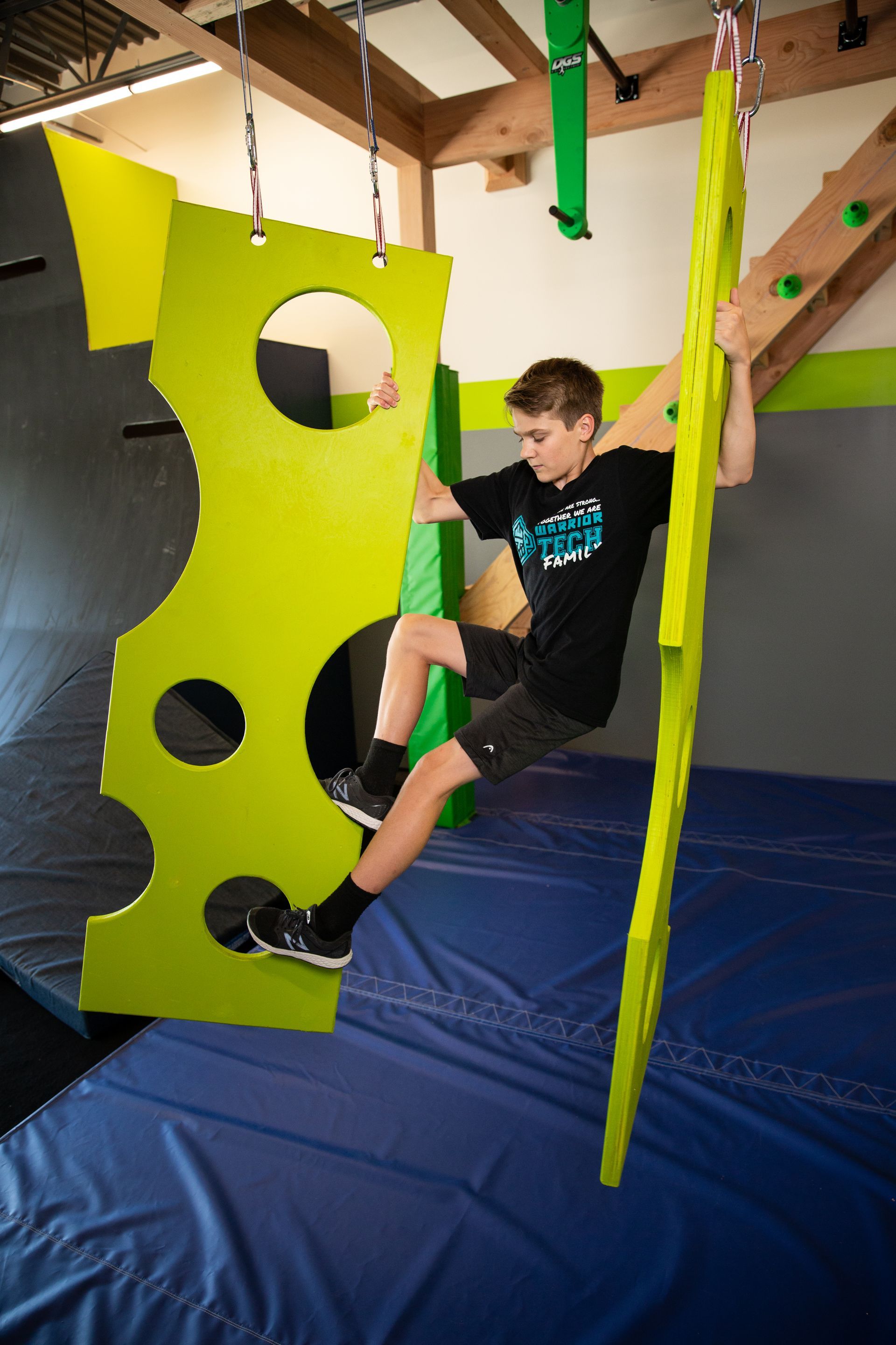 A young man is climbing a green cheese shaped wall.