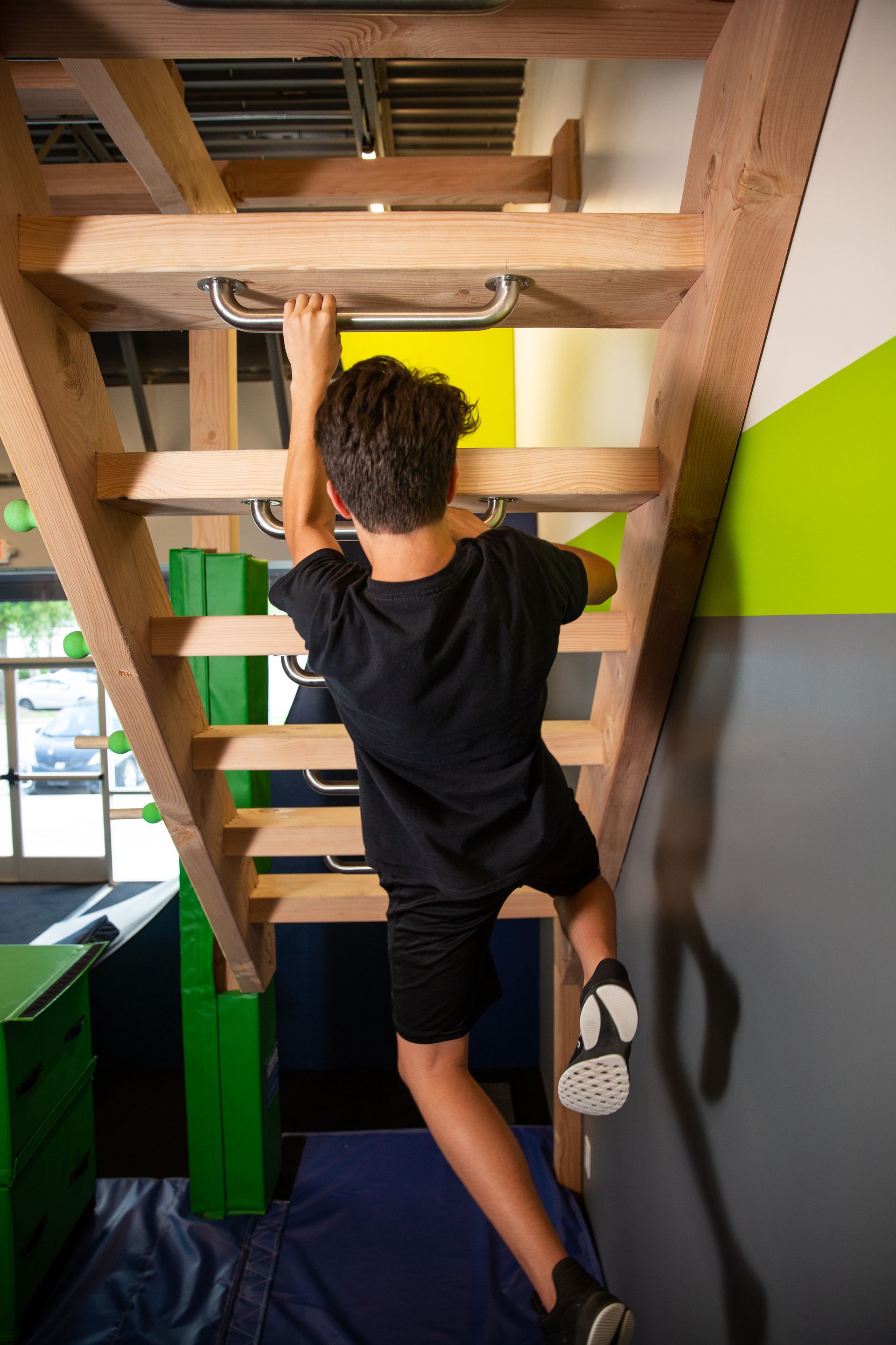 A young boy is climbing up a wooden ladder.
