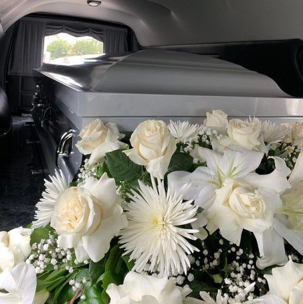 Casket in hearse with white flowers