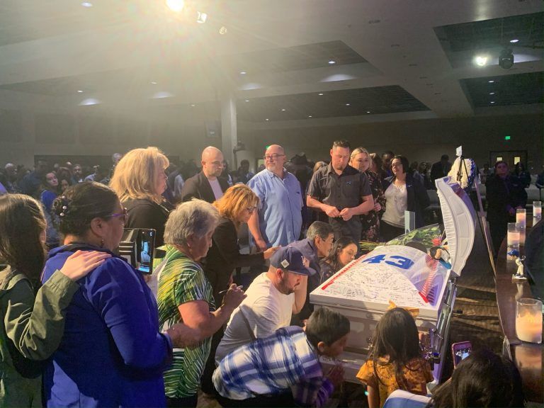 Indoor funeral services with family gathered around casket Chavez Funeral & Cremation Services, Inc. CA