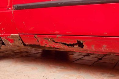 The side of a red car with a hole in it. | B & K Collision