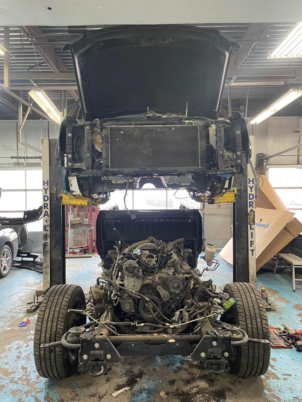 A car is being dismantled in a garage with the hood up. | B & K Collision